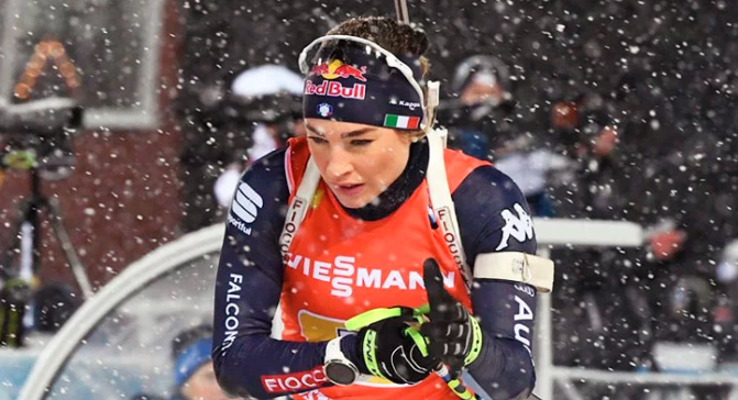 Dorothea Wierer in gara a Östersund, la tappa del debutto, intenta a rimettersi i guanti in uscita dal poligono, sotto una fitta nevicata.